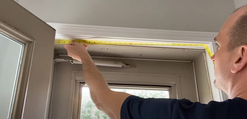 A man is measuring the door using a tape measure