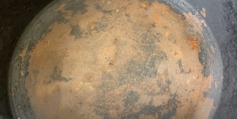 A rusty bottom of a large pan