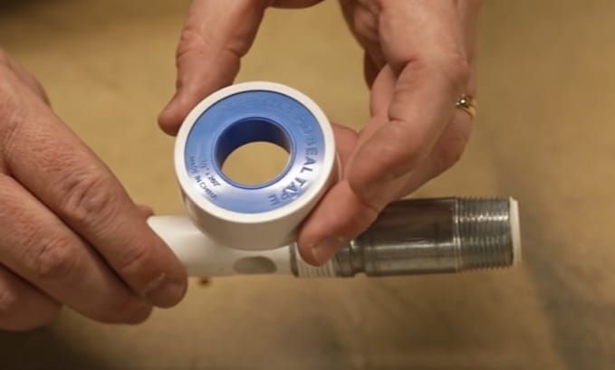 A person is holding a blue and white plastic pipe used for water heater repair