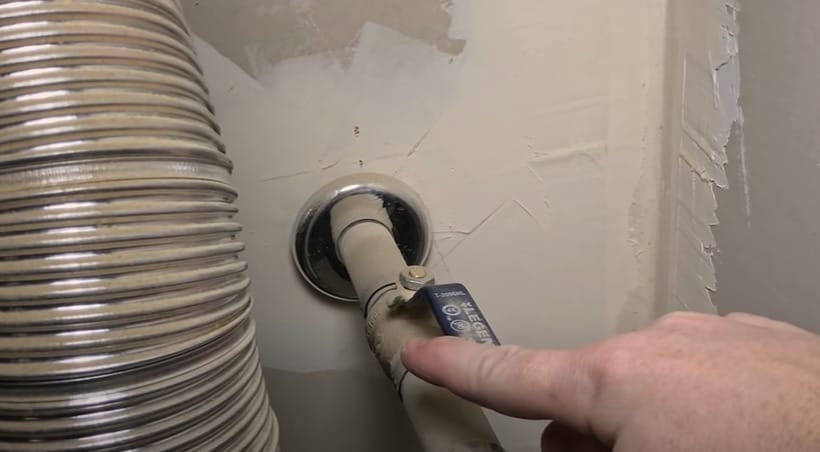 A person is pointing at a pipe connected to a water heater