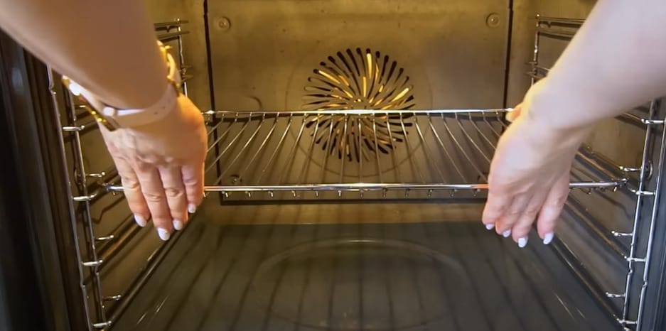 A woman putting back the clean oven rack