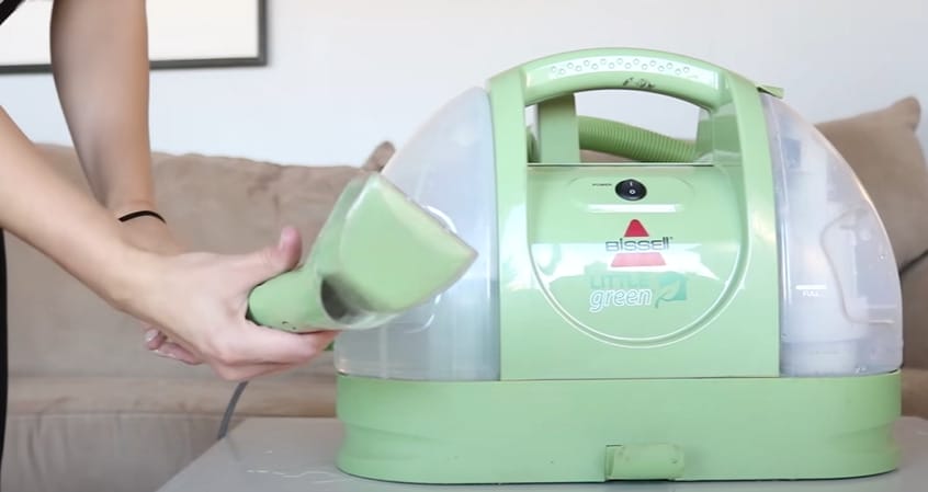 A person checking on the green vacuum cleaner