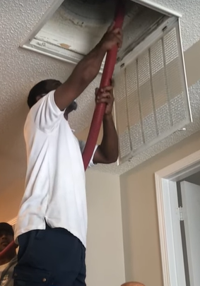 A man vacuuming the air ducts of a home
