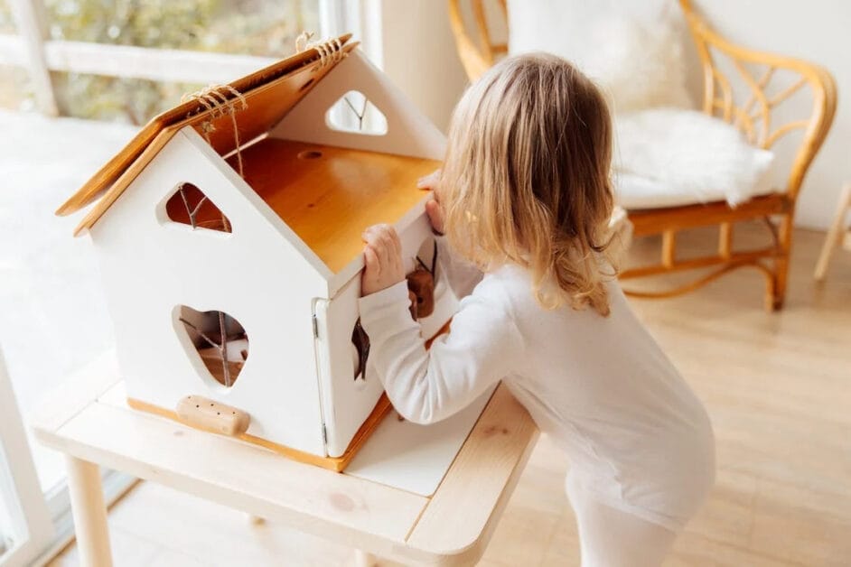A little girl playing with a toy house