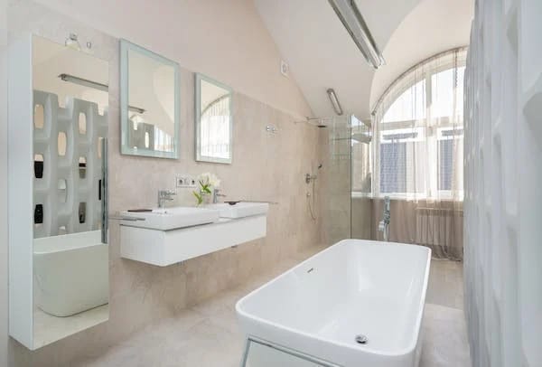 An immaculate bathroom with a tub, sink and mirror