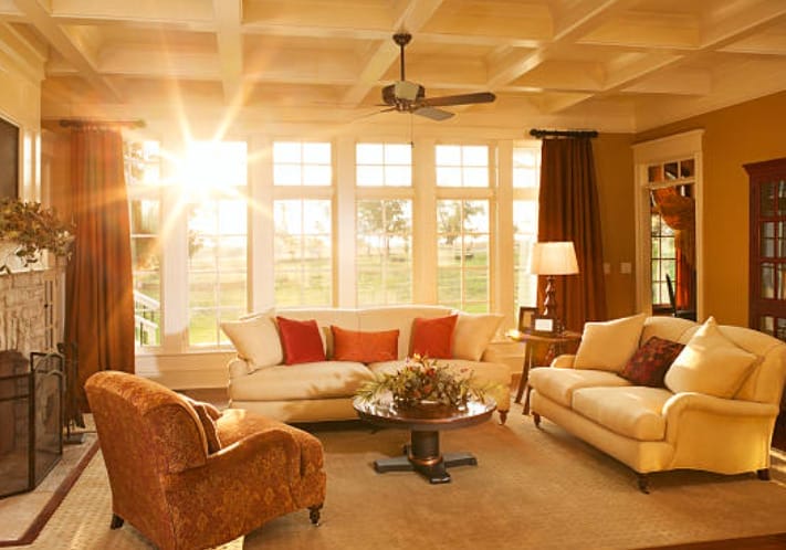 A cozy living room with comfortable couches and a warm sun peeking at the window