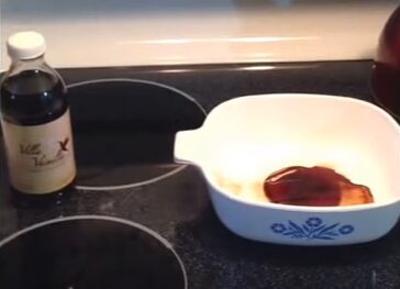 A bowl and a bottle of vanilla extract sitting on a stove top