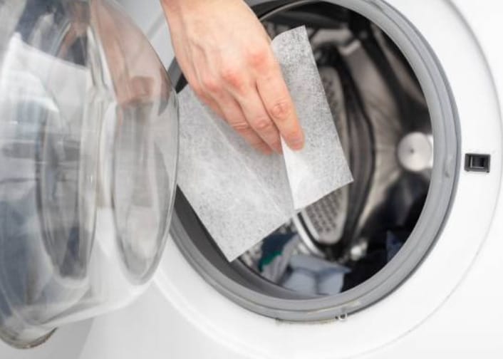 A person putting a dryer sheet on the washing machine