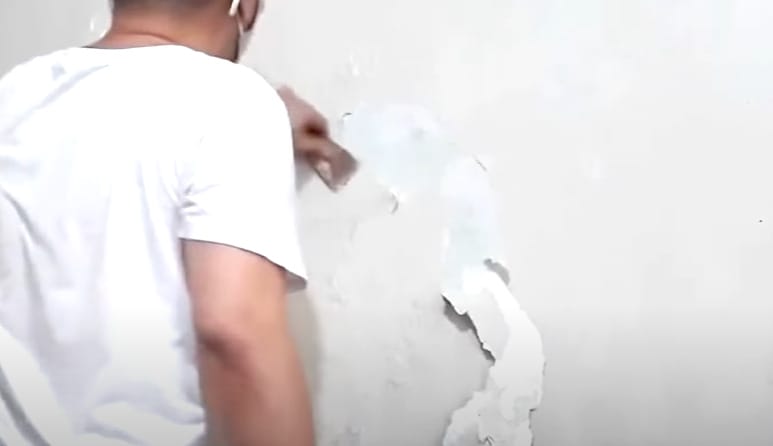 A man is stripping the wall paint