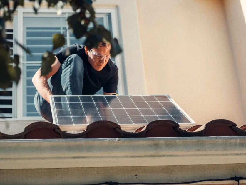 A man installing solar panels on the roof of a house