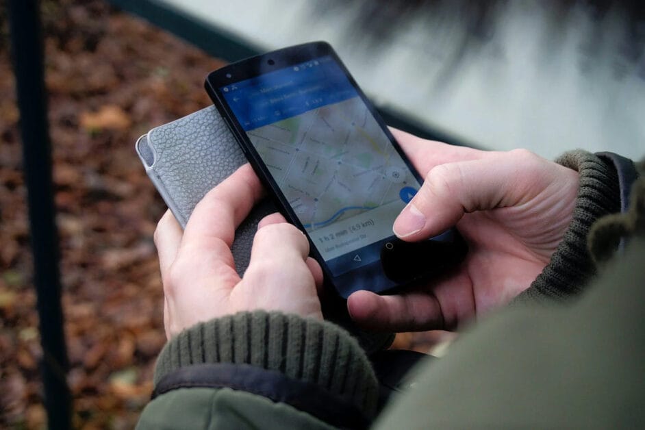 A person holding wallet and a cell phone with a map on it, searching for AC capacitor replacement tips.