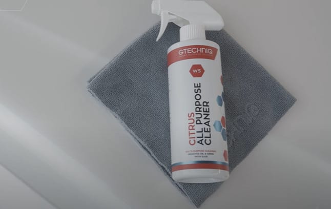 A bottle spray of cleaner with a cloth on top of it
