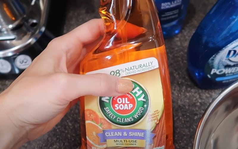 A person holding a bottle of oil soap