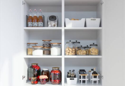 A grease-stained white kitchen cabinet with jars of food on it