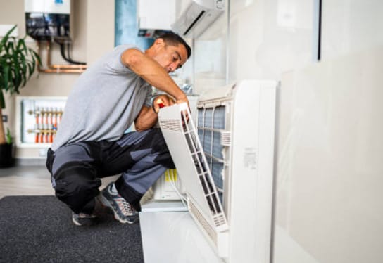 A man is sweating while fixing an air conditioner in a room