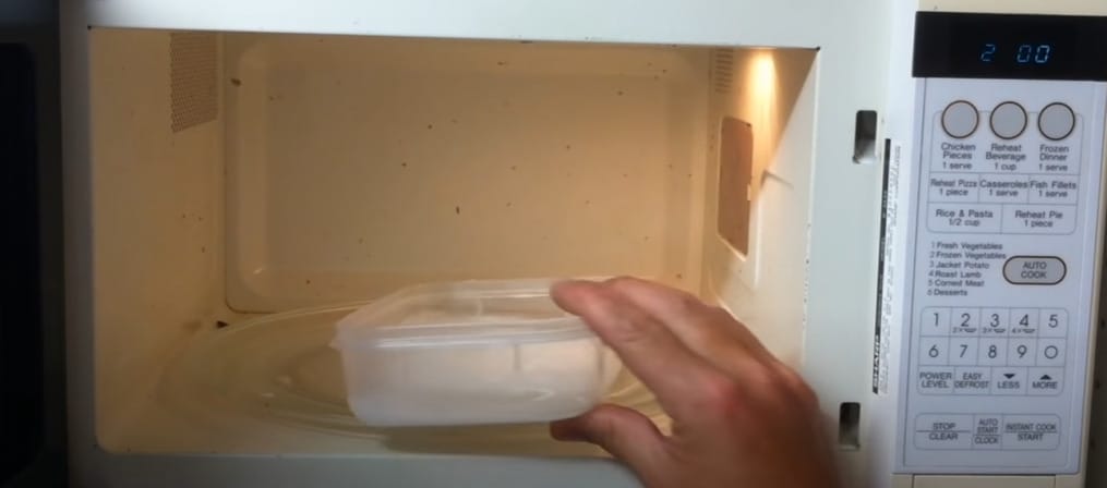 A person putting a bowl on the microwave