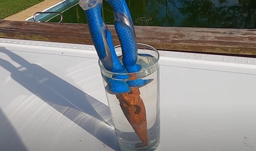 A rusty plier soaked with a glass of water solution in a glass