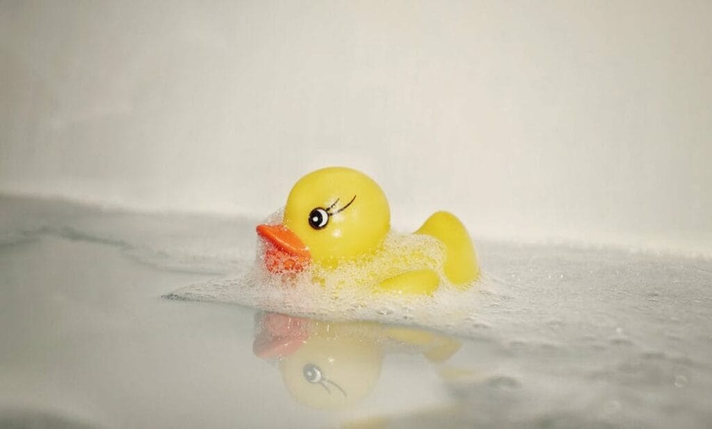 A yellow rubber duck is floating in a clean bath tub