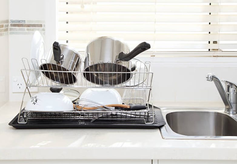 A kitchen sink with pots and pans on a rack