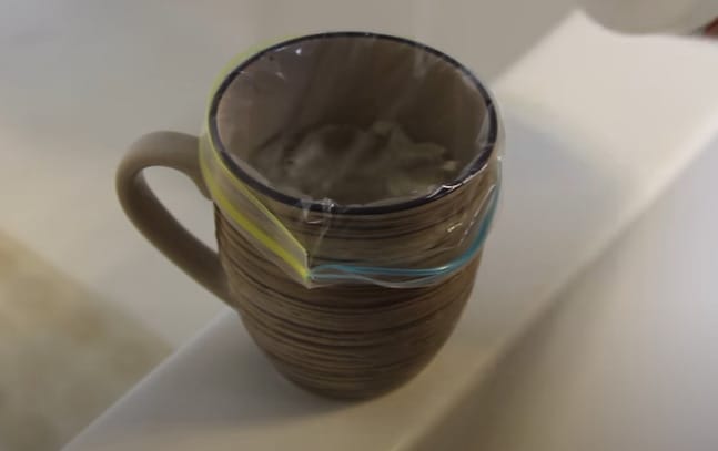 A mug is sitting on the edge of a clean bathtub