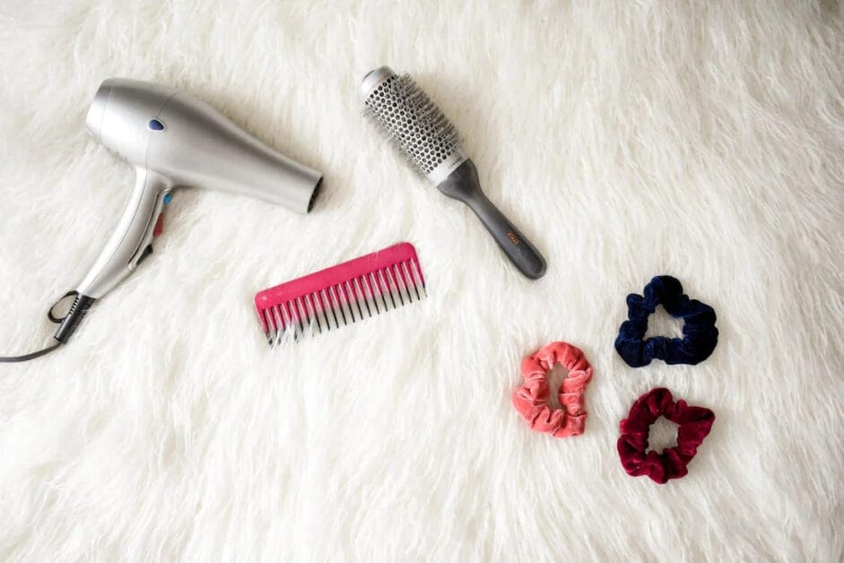 A hair dryer and hair accessories on a white fur rug