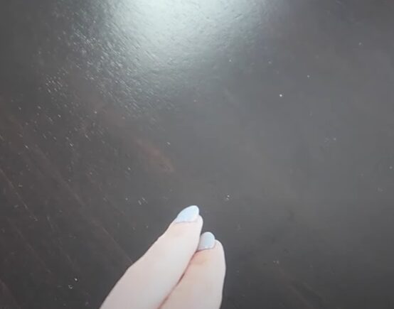 A person's hand with blue nails on a table
