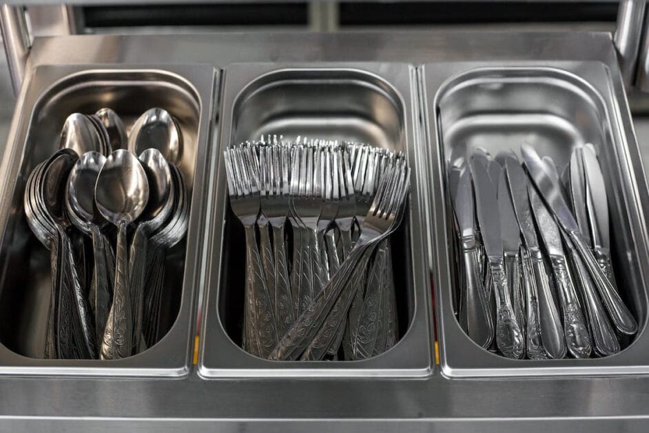 Forks and spoons in a metal tray in a restaurant