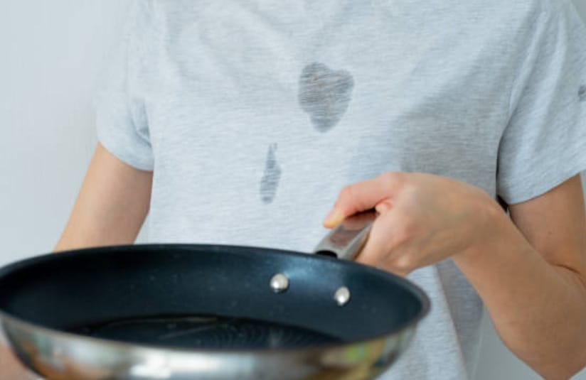 A woman is holding a frying pan with a stain on it, exploring baking soda hacks to remove the stain.