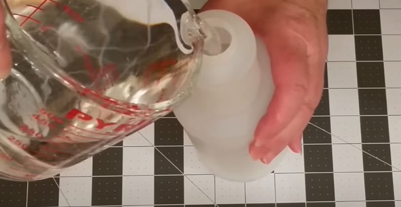 A person pouring homemade liquid into a bottle
