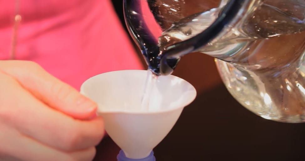A woman pouring a distilled water into the mixture
