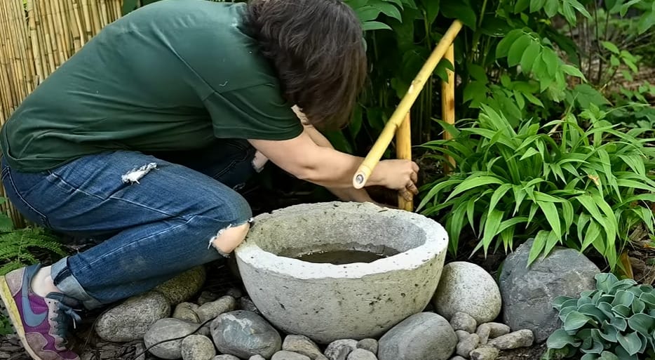 A woman putting a bamboo water pipe in a concrete bowl