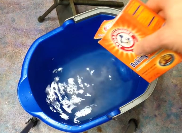 A person is pouring a box of baking soda into a jar of water