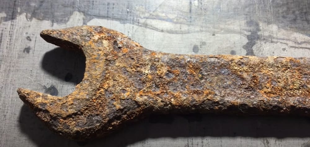 An old rusty wrench, made of metal, on a table