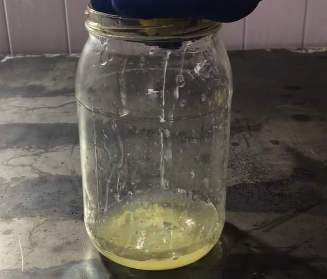 A person is pouring a lemon juice in a mason jar