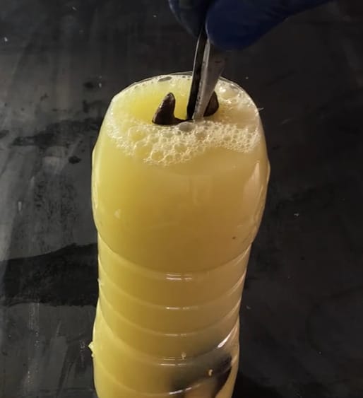 A piece of metal being soaked in a mixture of lemon juice and salt