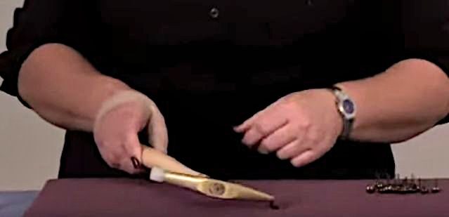 A person using a tack hammer on a fabric laid on the table