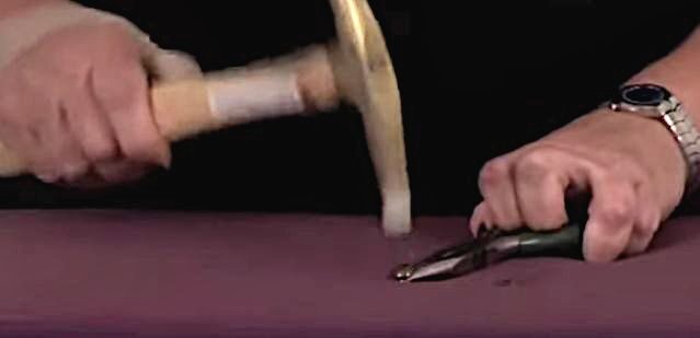 A person using a tack hammer and plier on a nail