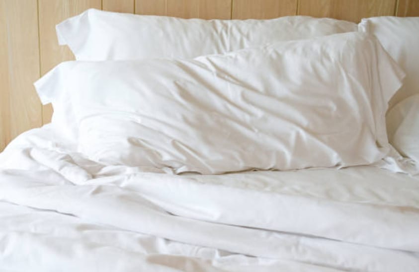 A bed with white sheets and pillows