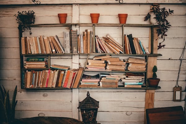 A wooden wall shelf full of books