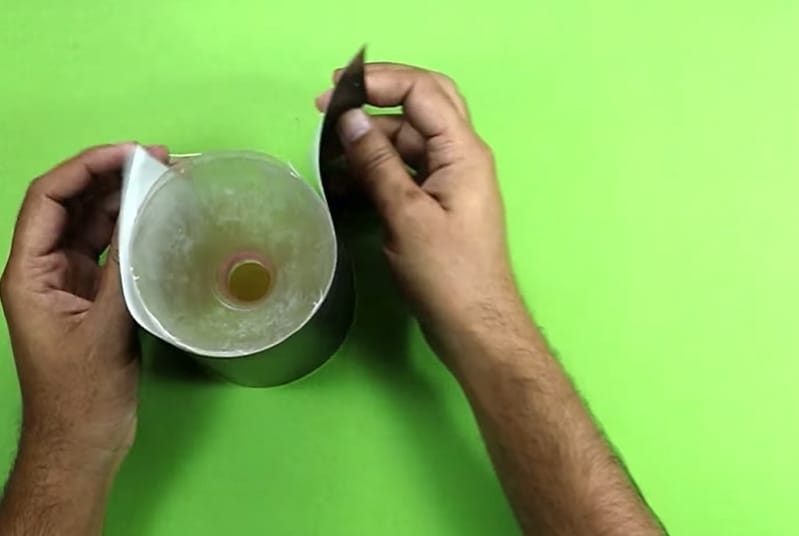 A person covering the jar mixture of water and brown sugar with a black paper
