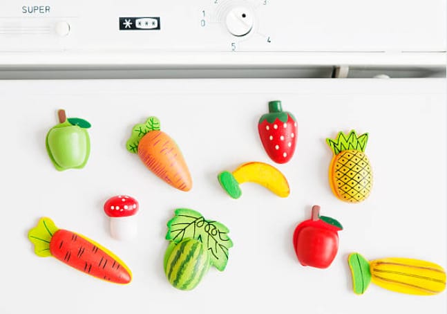 A home refrigerator adorned with a bunch of fruit magnets