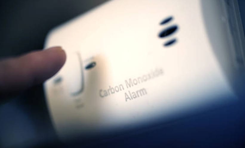 A person about to press the button of a carbon monoxide alarm device