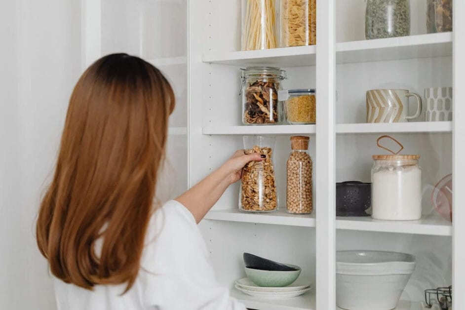 A woman is putting granola into a pantry shelve