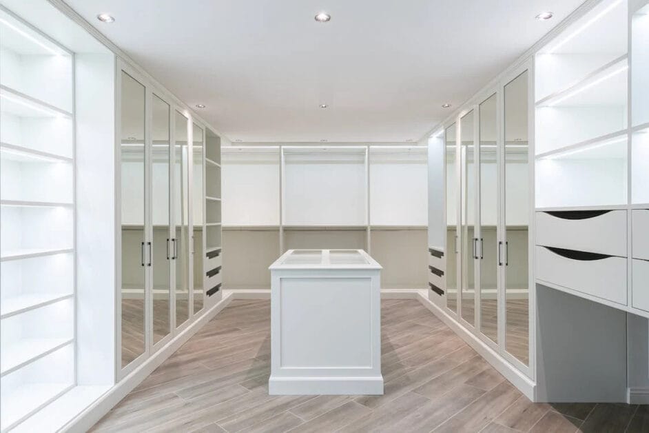 An empty walk-in closet with white cabinets and drawers