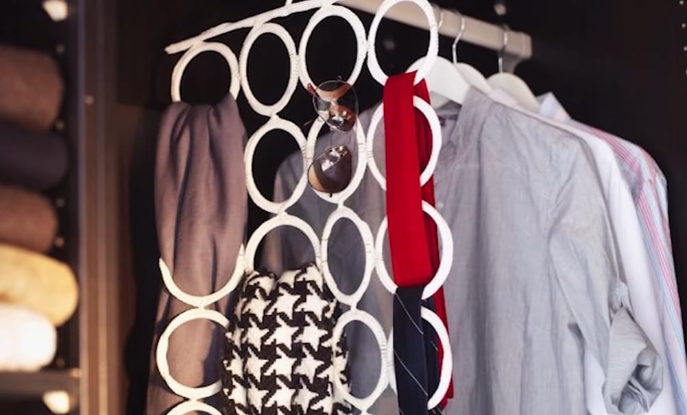 A closet with clothes and accessory hanger hanging on closet rack