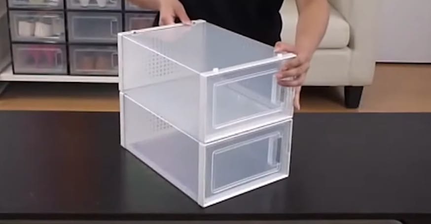A person holding a white transparent stackable shoe bins