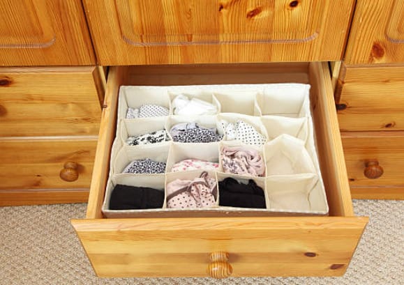 A drawer of clothes in a wooden cabinet