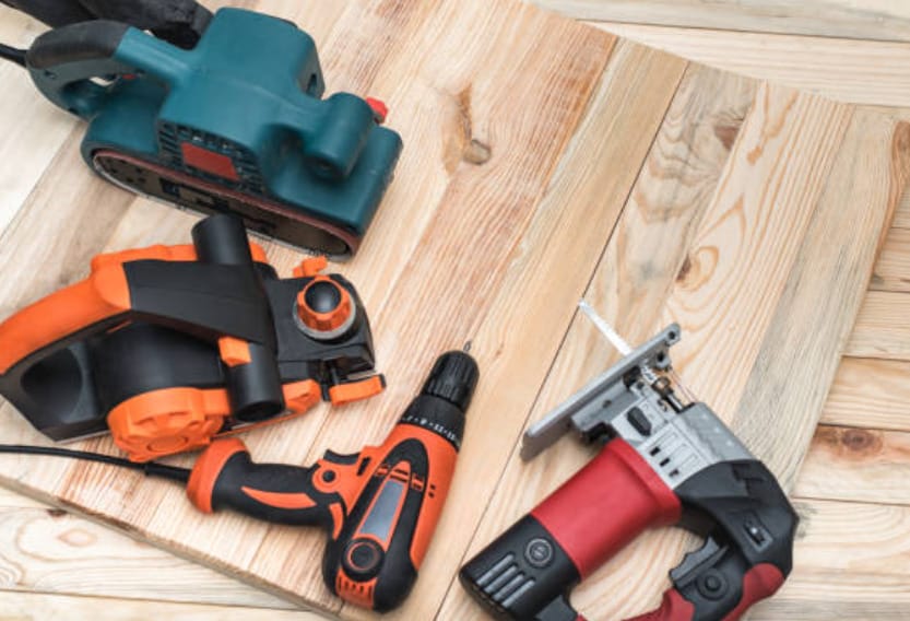 A variety of power tools arranged on a wooden board