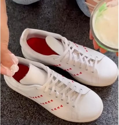 A woman putting baking soda on a rubber a pair of shoes