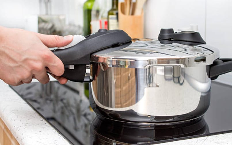 A person using an electric pressure cooker on top of a stove